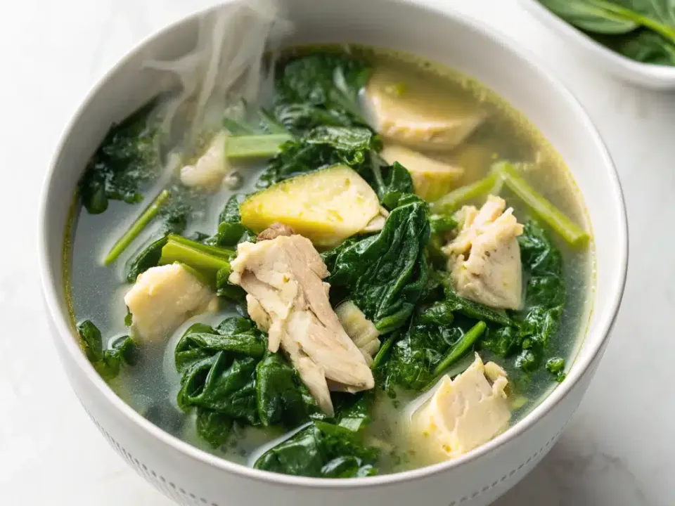 Bowl of creamy spinach artichoke chicken soup topped with Parmesan and parsley