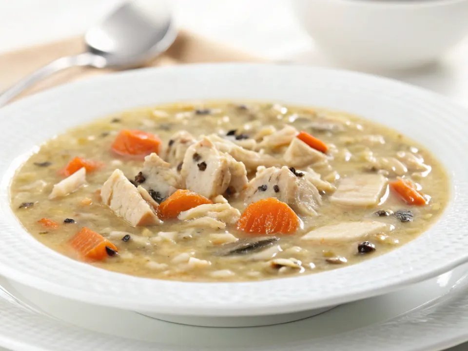Bowl of creamy chicken and wild rice soup with carrots and visible wild rice grains