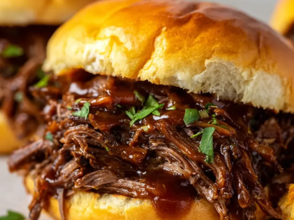 Shredded beef in a dark glossy sauce piled high on a soft golden sandwich bun