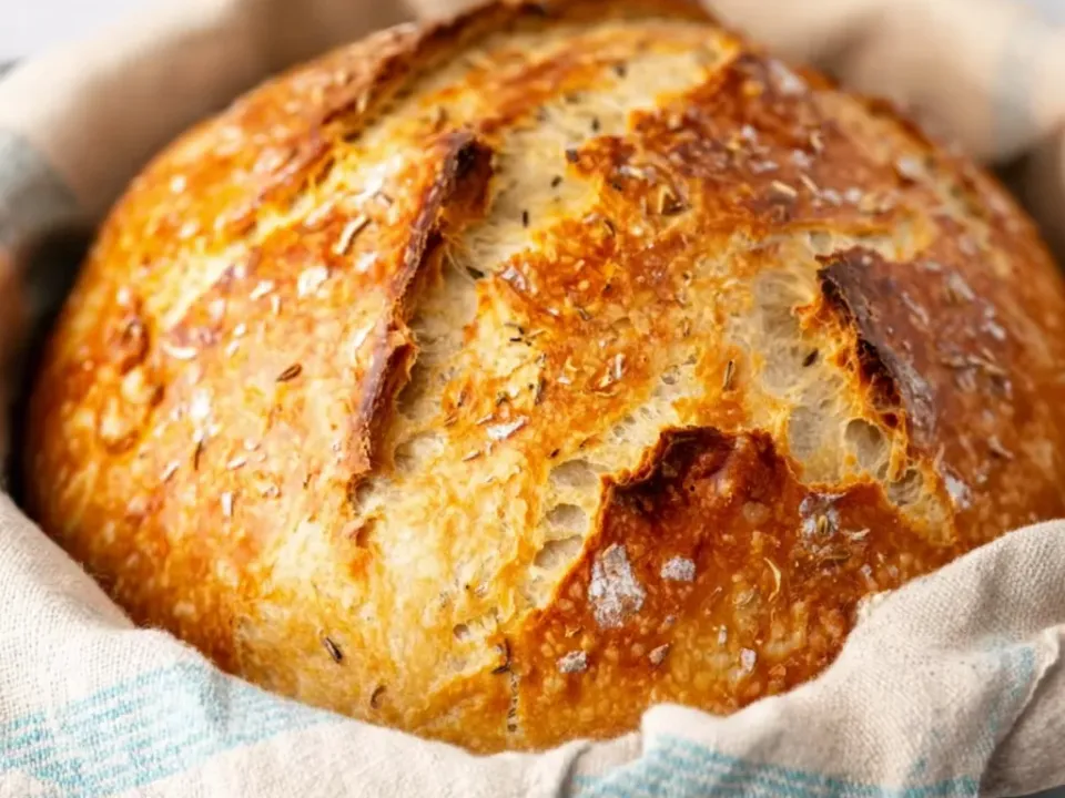 A round, deeply browned crusty artisan loaf with a floured, cracked top
